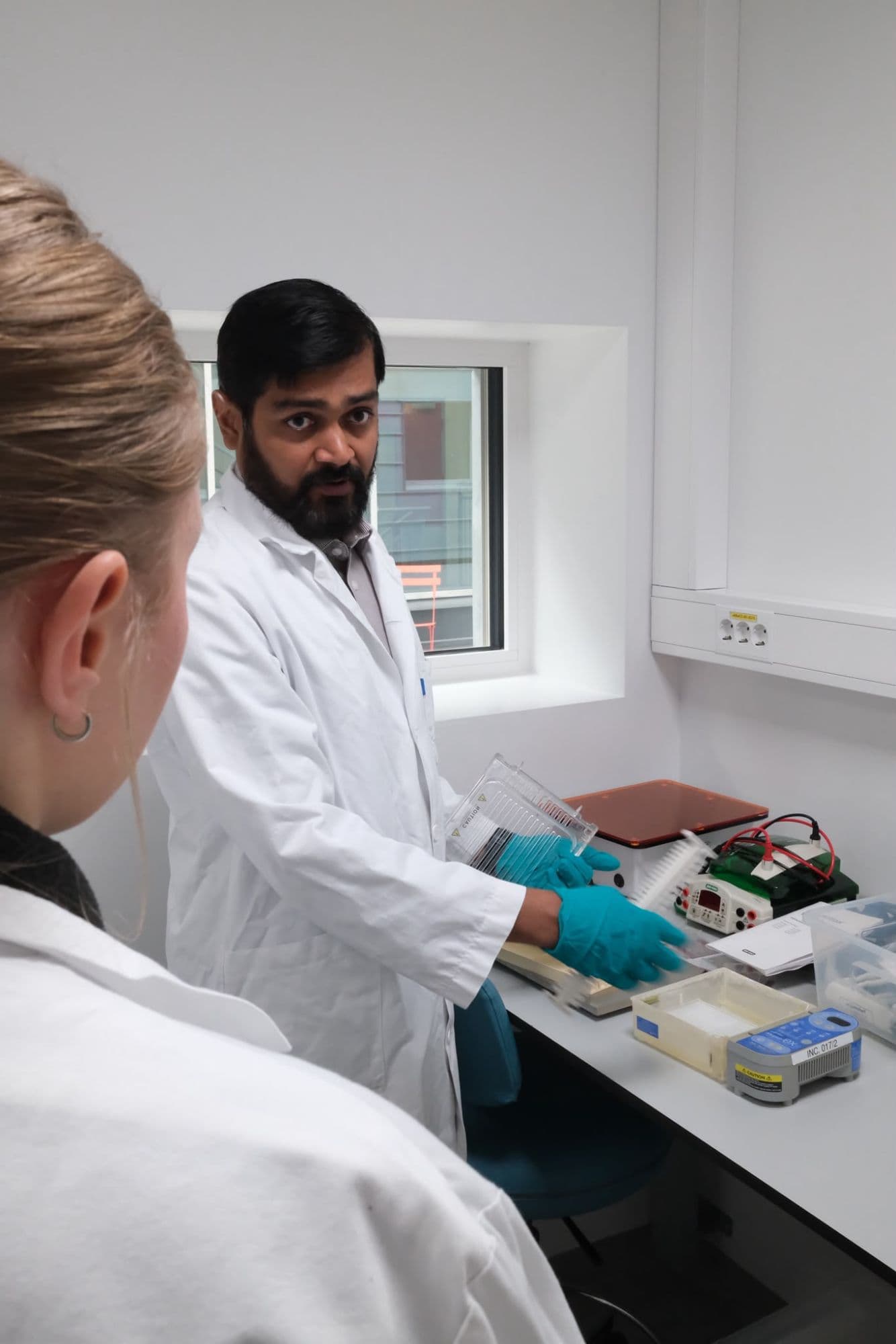 Researcher demonstrating laboratory equipment to a colleague